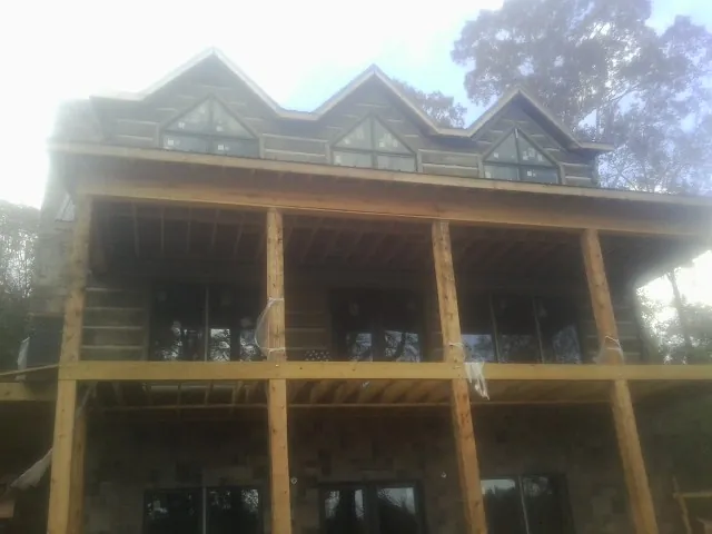 Dormers and porch framing on a large log home under construction — Roof Coating work by our crew in Marianna