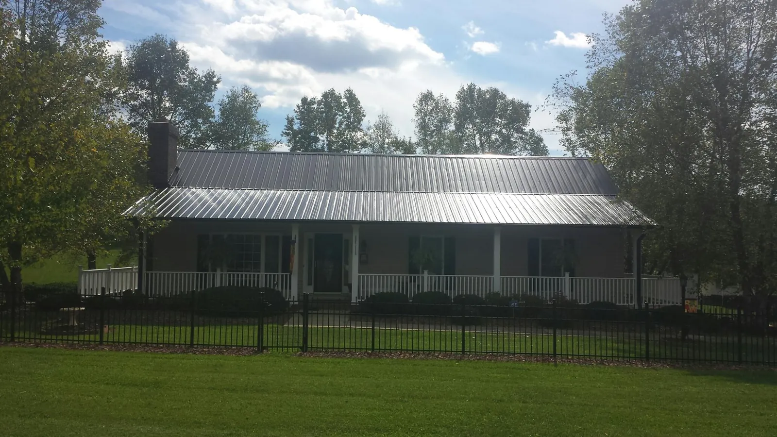 Gray metal roof on a brick ranch with a full width front porch — Gutter Guard Installation work by our crew in Marianna