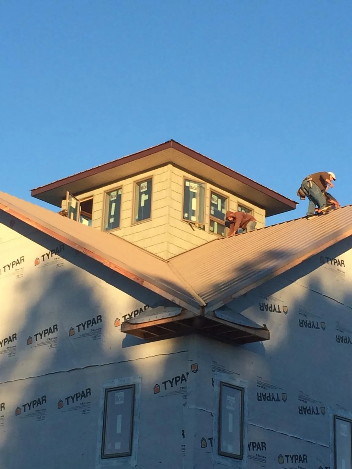 Roofers working around a rooftop cupola on a new metal roof at sunset — Roof Waterproofing in Marianna by Roofing Brothers